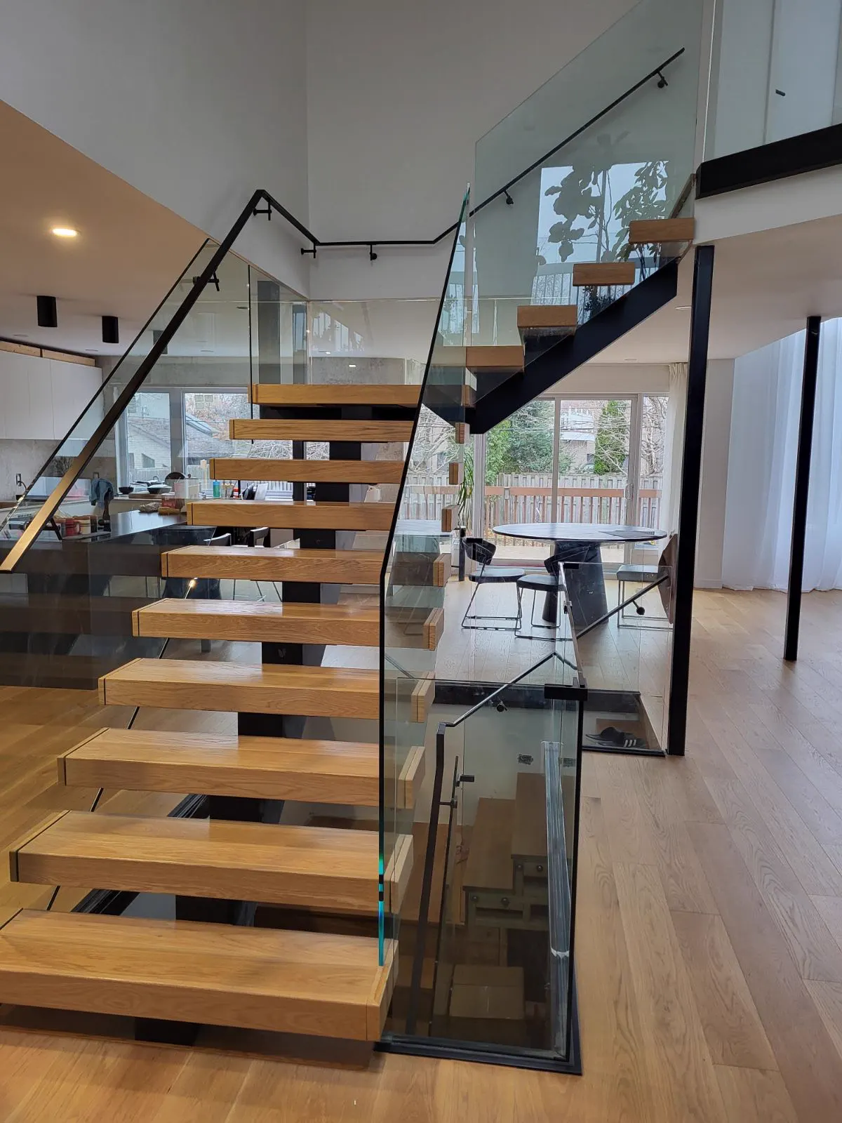 Escalier aux marches de bois flottantes et garde-corps de verre